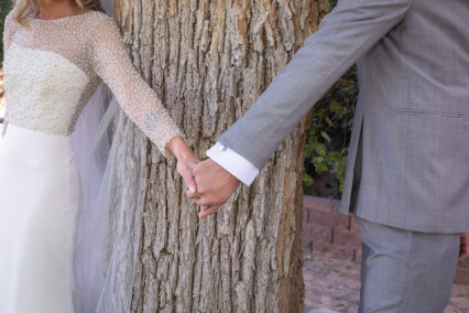 bride and groom holding hands by tree