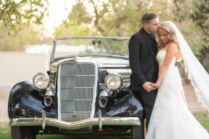 bride and groom in front of car